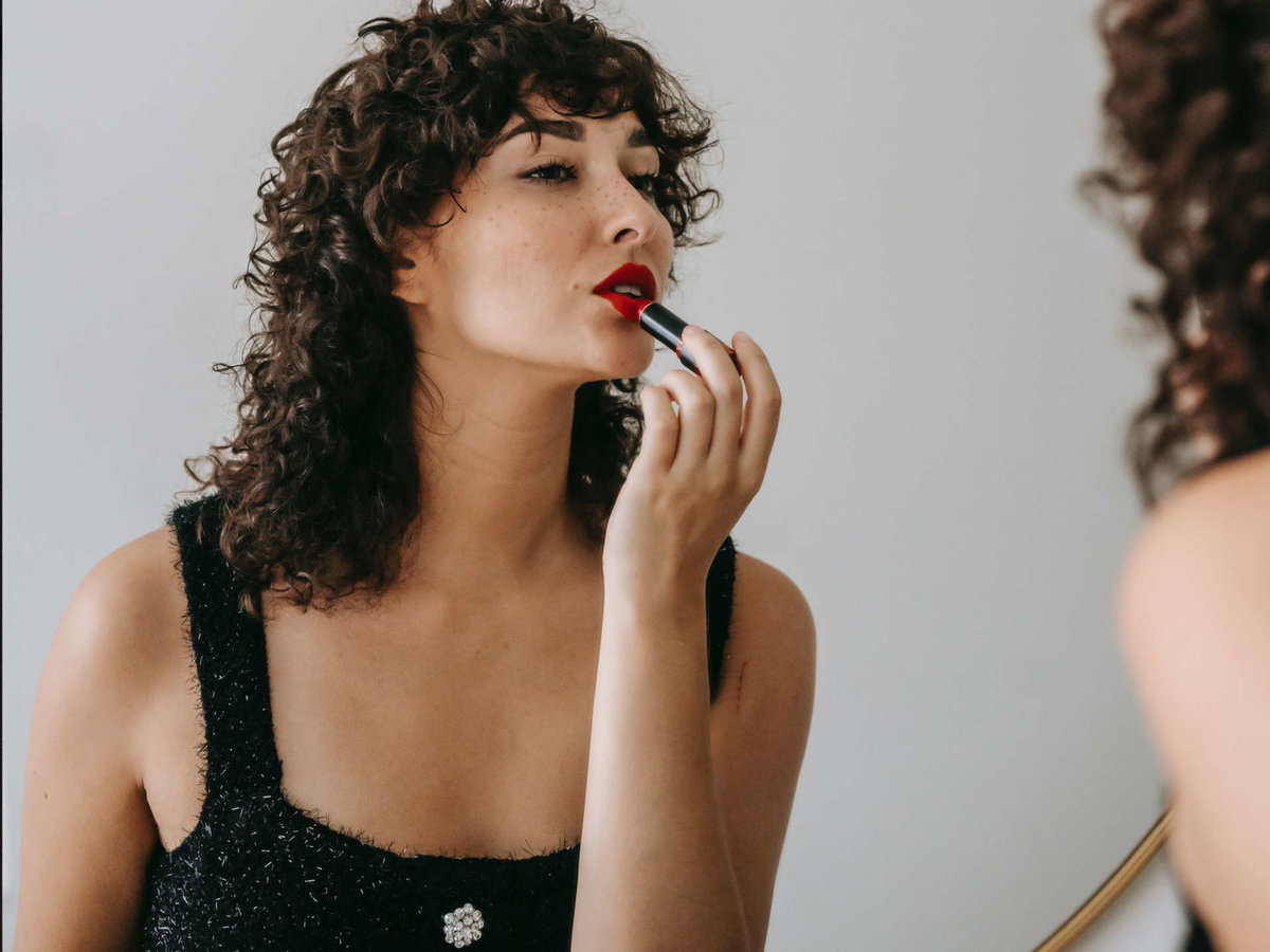 Frau trägt roten Lippenstift auf.
