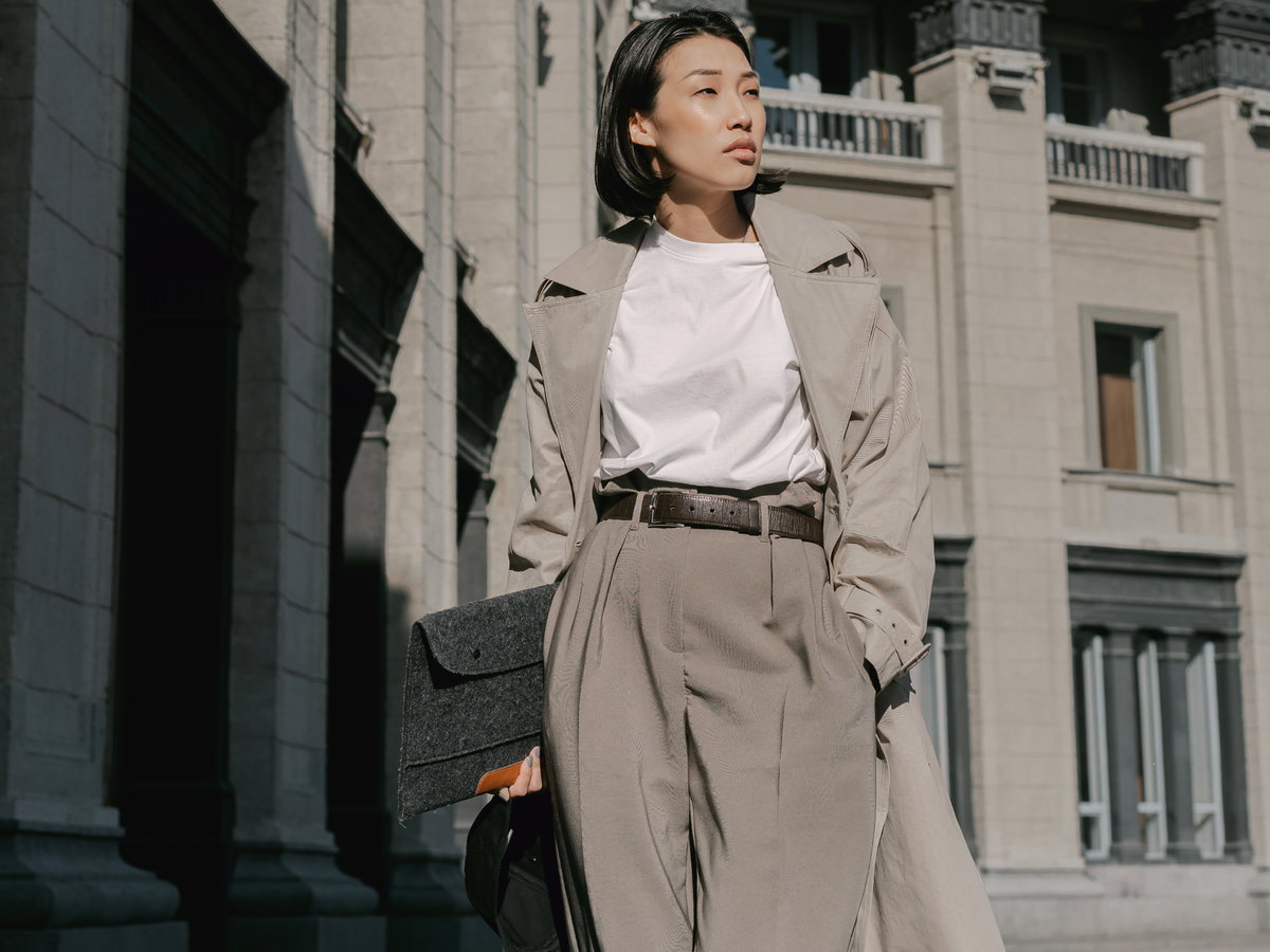 Frau trägt Trenchcoat, weite Hose und weißes T-Shirt