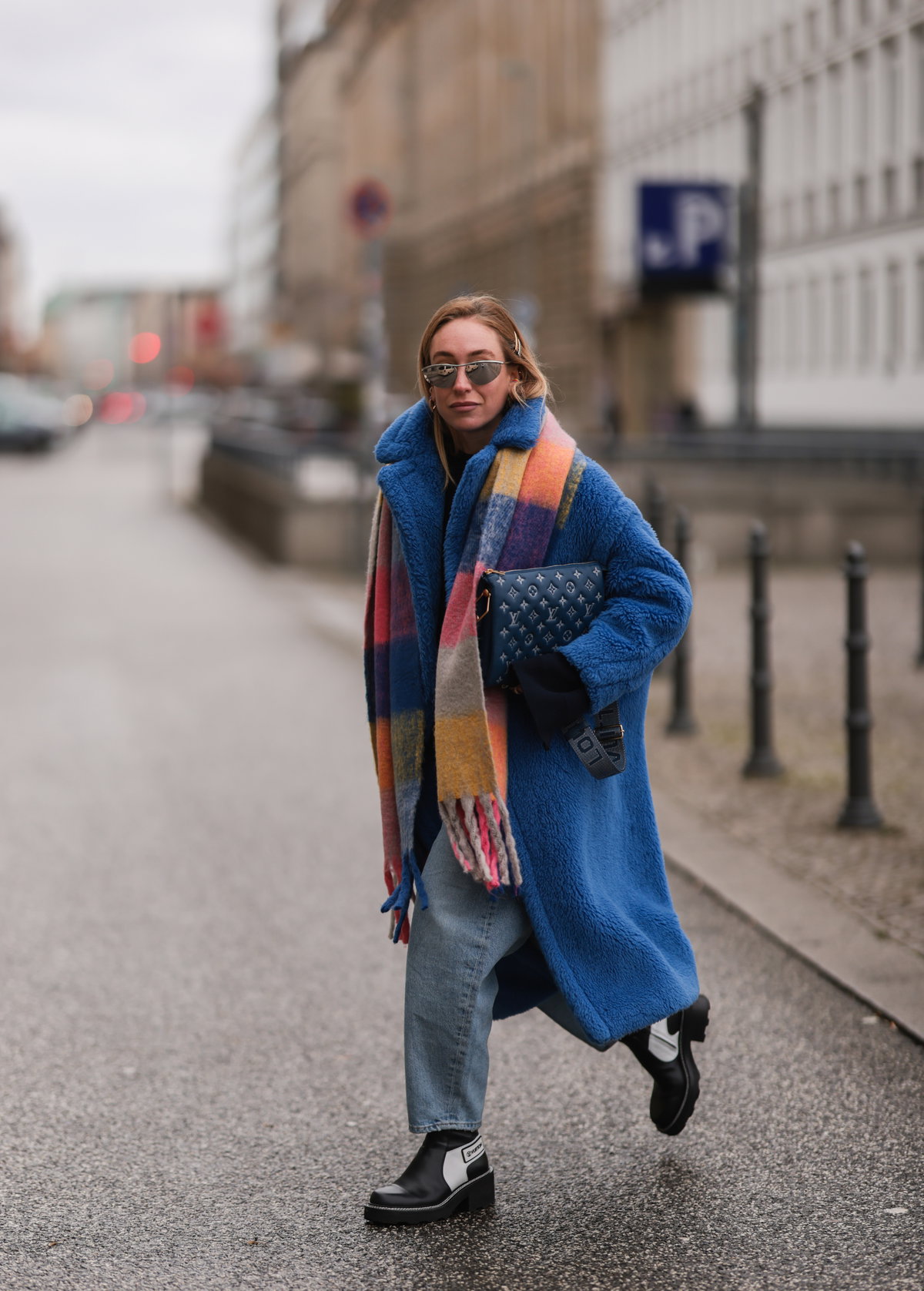 Streetstyle Frau trägt Jeans, blauen Mantel und bunt karierten Schal