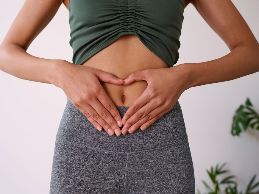 Frau mit Händen in Herzform auf Bauch