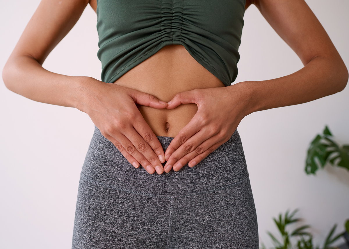Frau mit Händen in Herzform auf Bauch