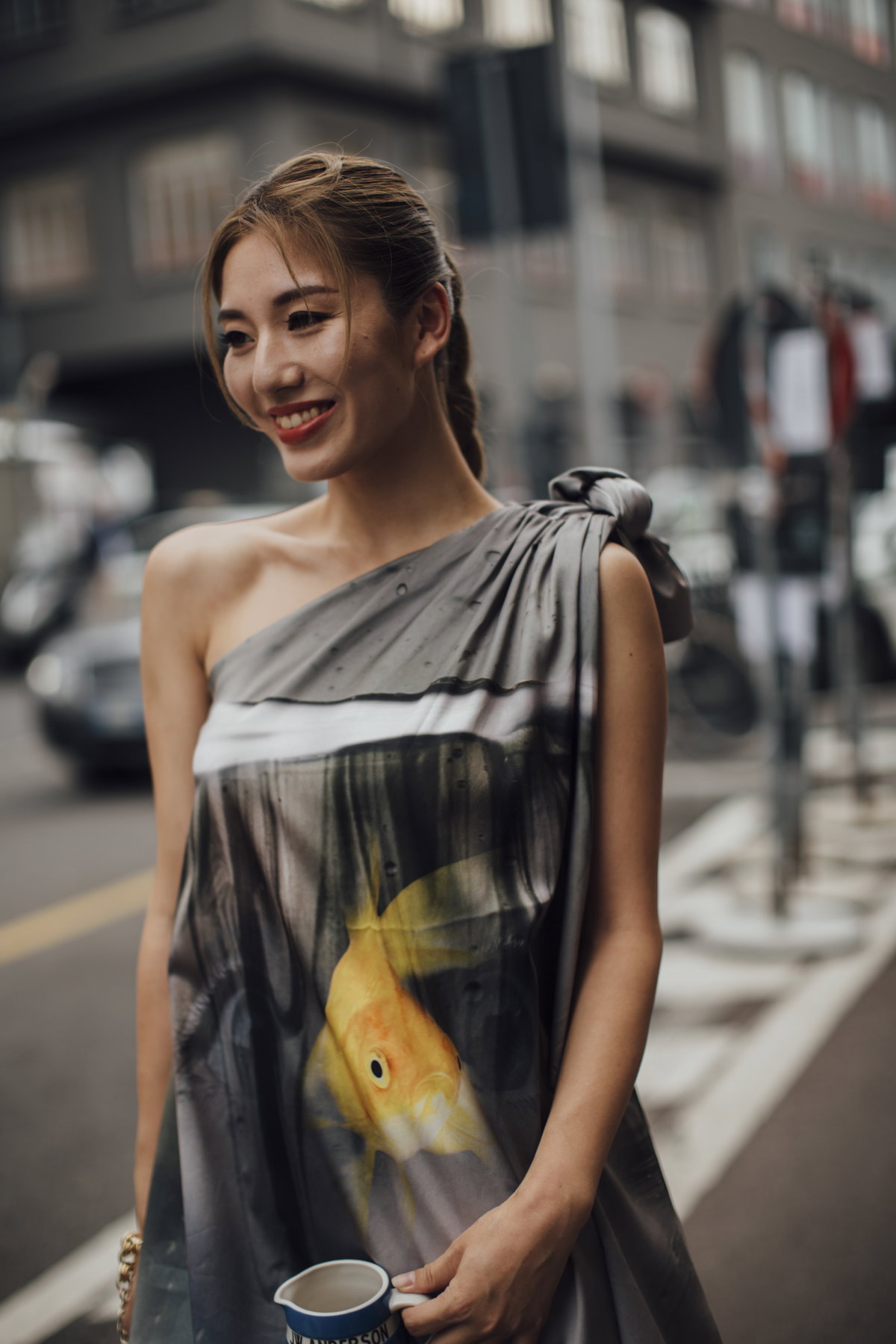 Mailand Fashion Week Frau trägt Kleid und Zopf lächelt