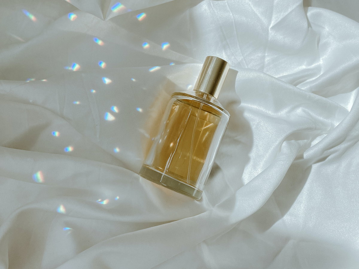 Parfum Flakon liegt auf einem Bettlaken mit Licht und Schatten