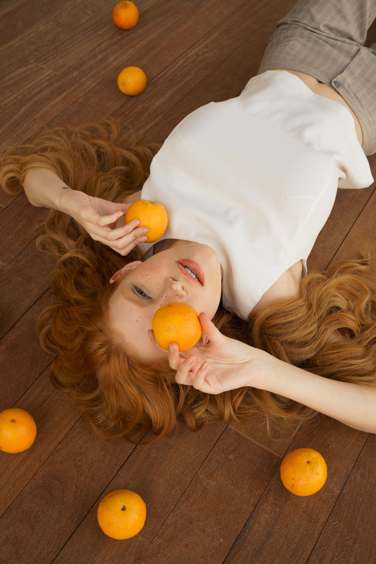 Frau mit orangenen Haaren haelt Orangen