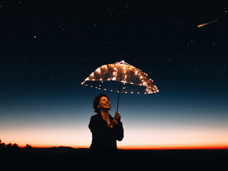 Frau in der Nacht mit leuchtendem Regenschirm
