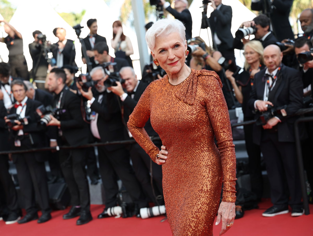 Maye Musk auf den Cammes Filmfestspielen mit grau weißen Haaren und bronzefarbenen Kleid kurze Haare