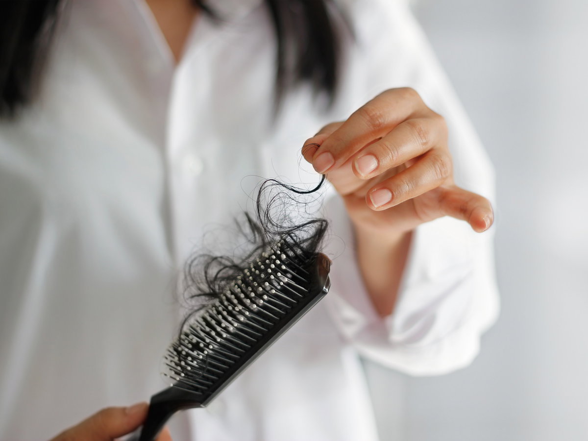 Frau hält Bürste mit Haaren in der Hand