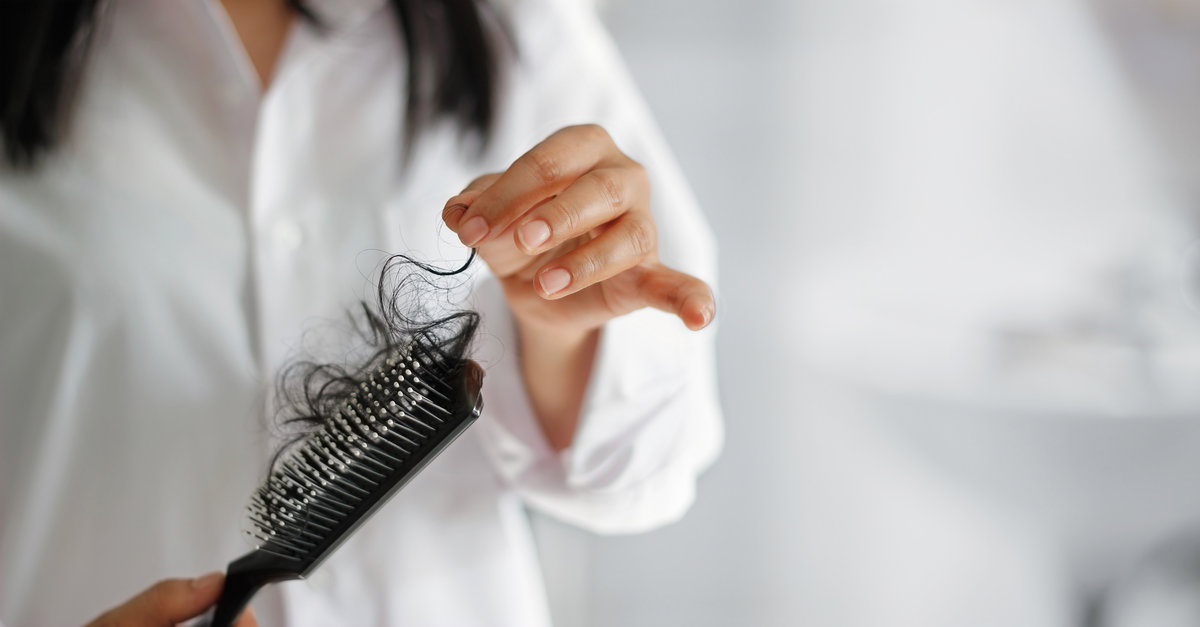 Frau hält Bürste mit Haaren in der Hand
