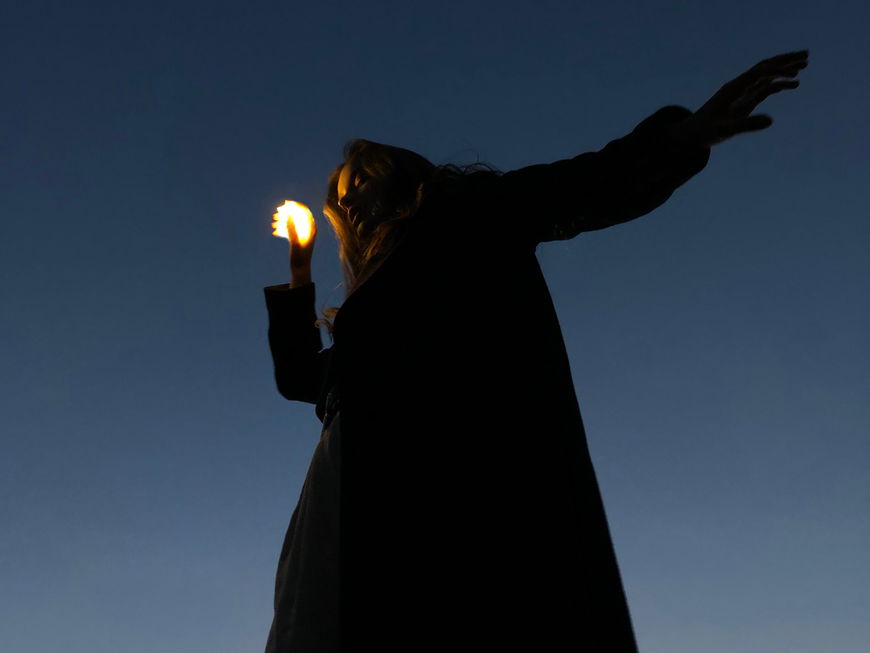 Frau hält eine kleine Lichtkugel in der Hand