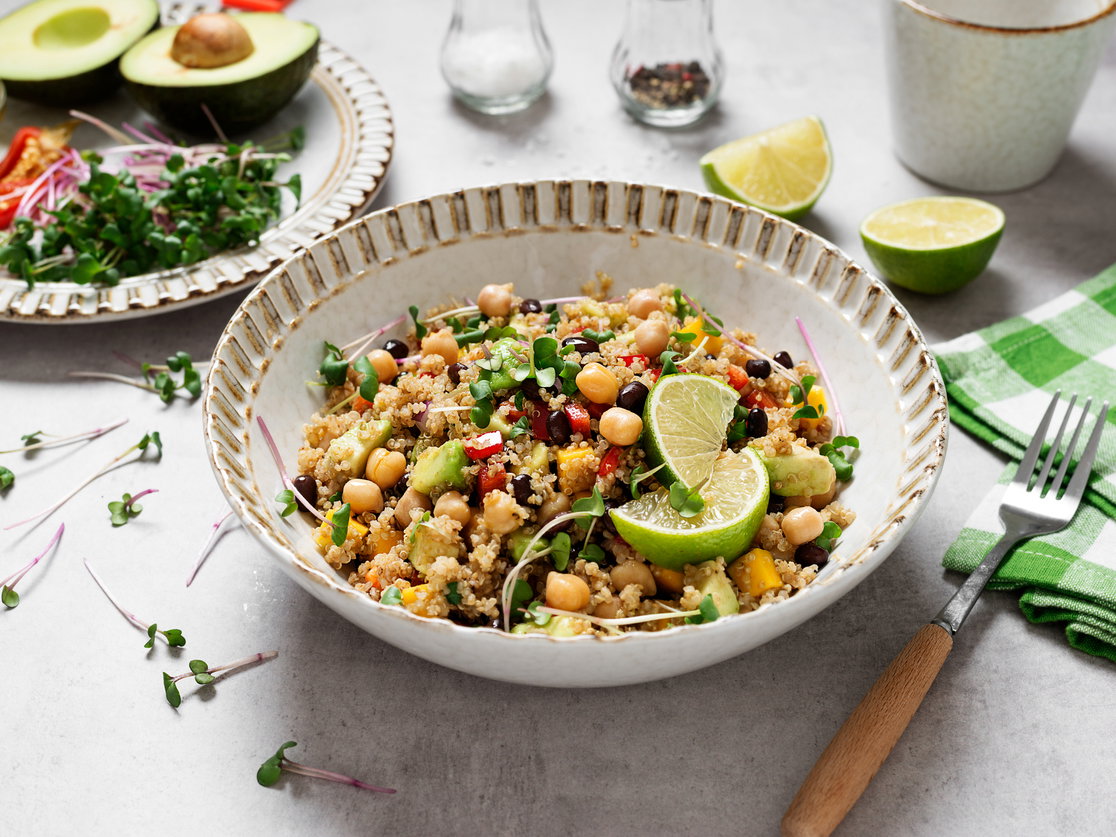 Ein Teller Quinoa-Salat mit Kichererbsen und Limette steht auf einem Tisch