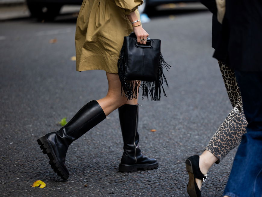 Frau mit schwarzem Stiefel und Fransen-Handtasche