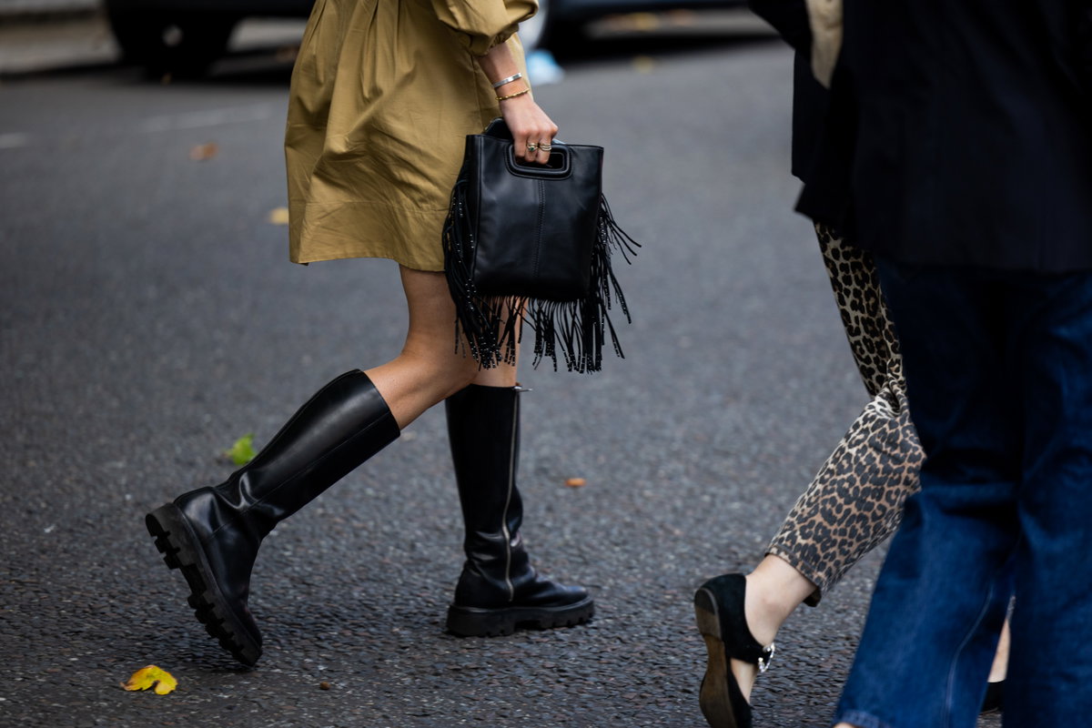 Frau mit schwarzem Stiefel und Fransen-Handtasche