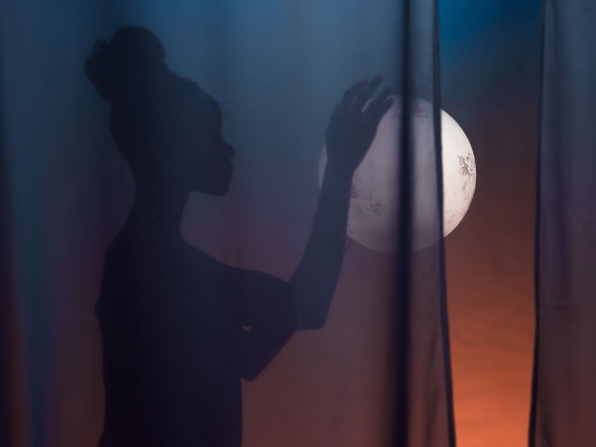 Frau mit Dutt hält den Vollmond in der Hand