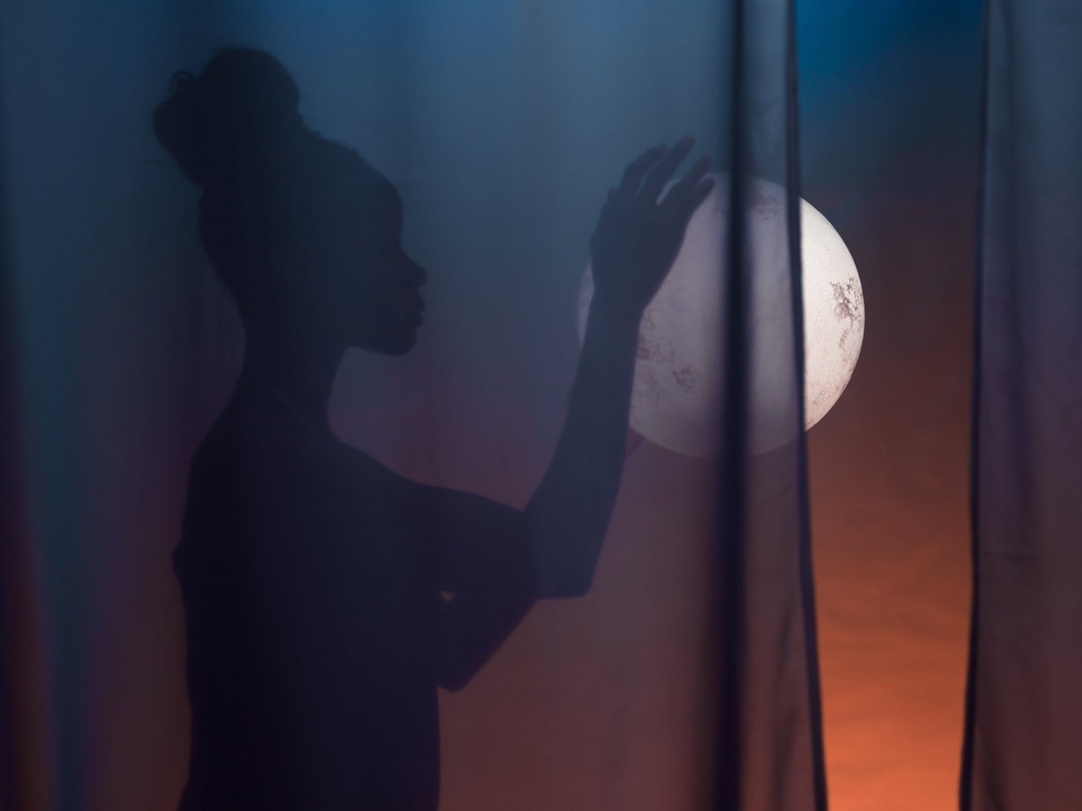 Frau mit Dutt hält den Vollmond in der Hand