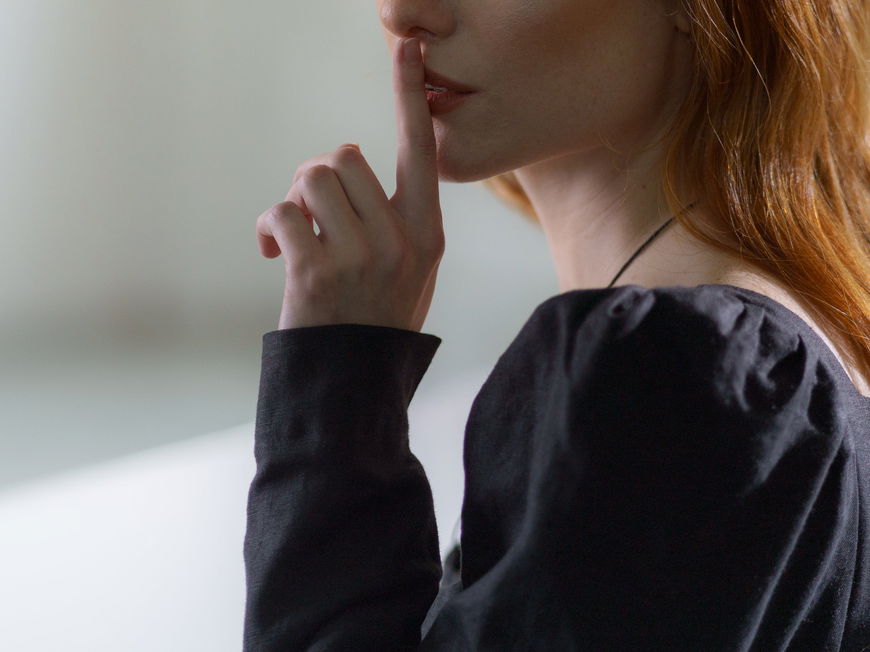 Frau hält ihren Zeigefinger vor ihren Lippen