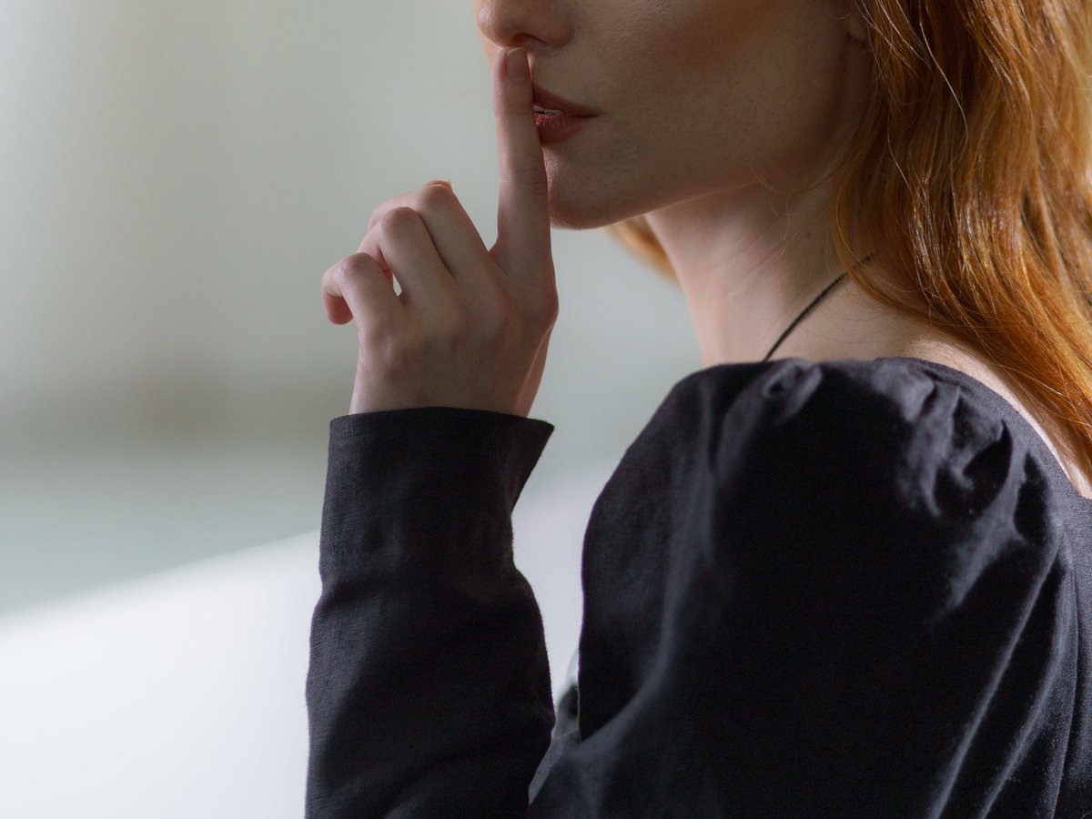 Frau hält ihren Zeigefinger vor ihren Lippen