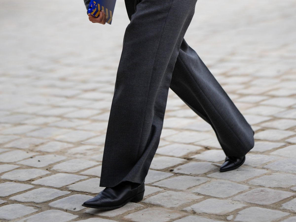 Stylische Frau trägt auf Paris Fashion Week Ankle Boot und graue weite Hose plus Jacke
