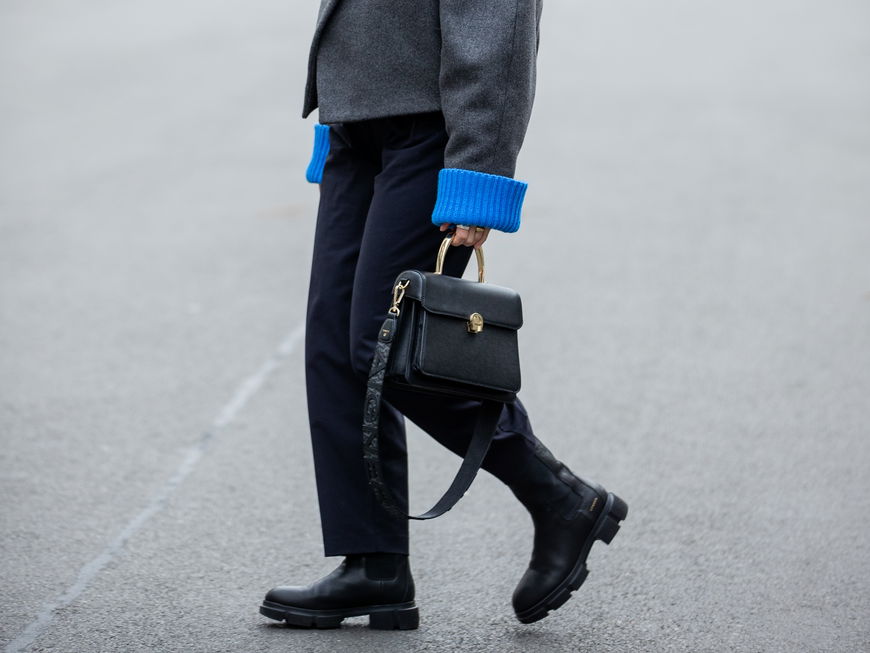 Aline Kaplan trägt schwarze Aigner Tasche schwarze Boots und graue Wolljacke