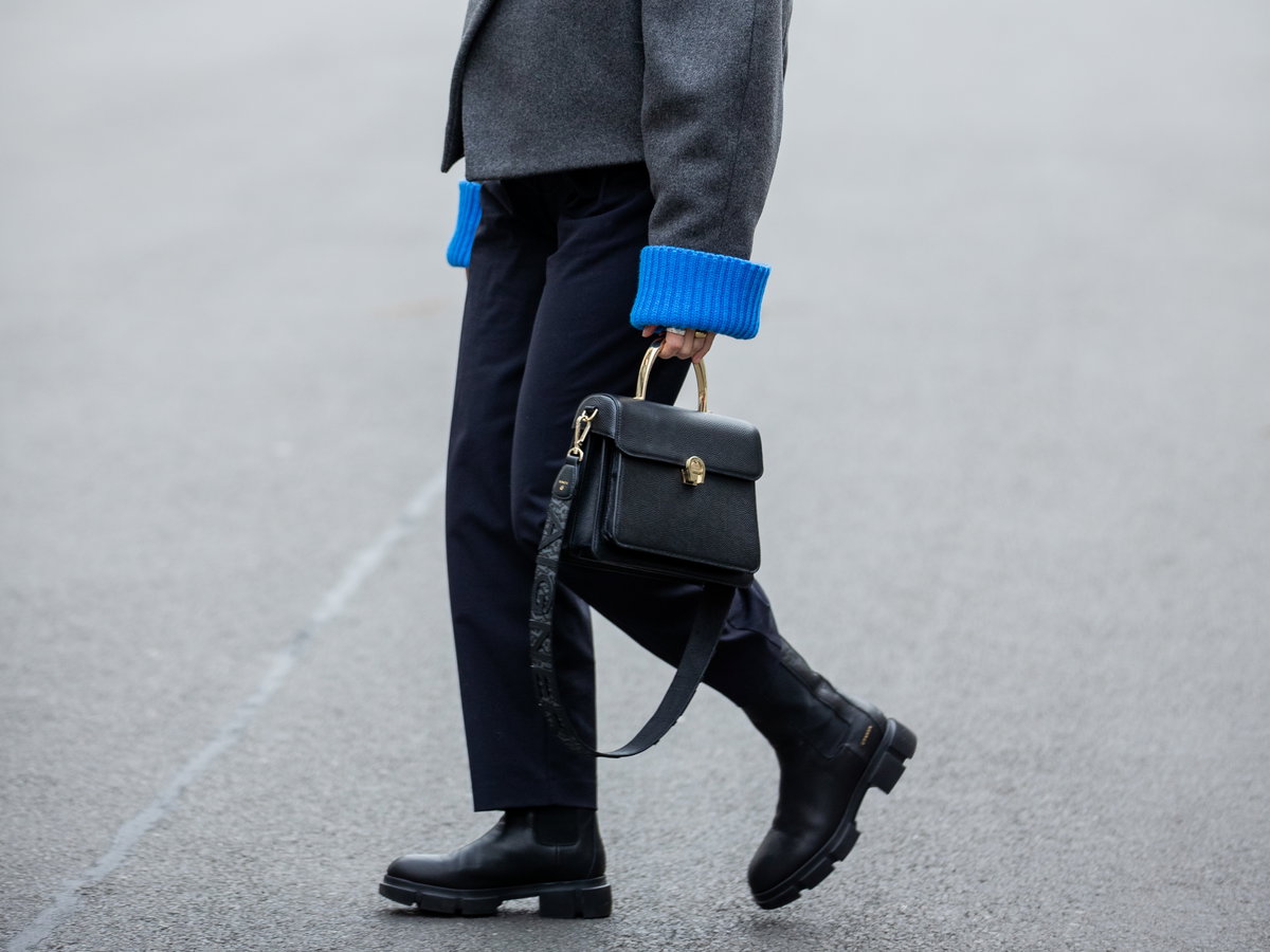 Aline Kaplan trägt schwarze Aigner Tasche schwarze Boots und graue Wolljacke