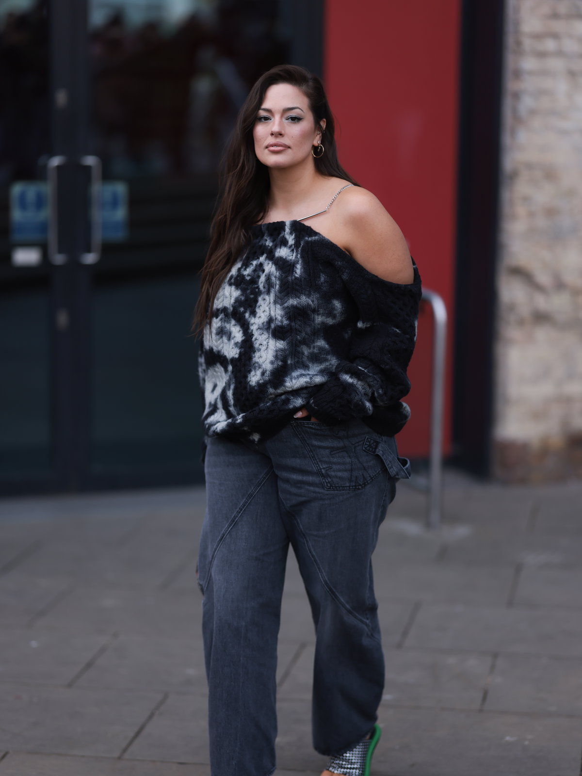 Ashley Graham trägt Off Shoulder Pullover mit grauer Jeans und High Heels