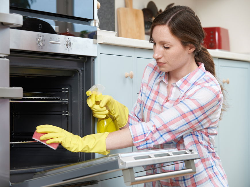 Frau putzt Backofen