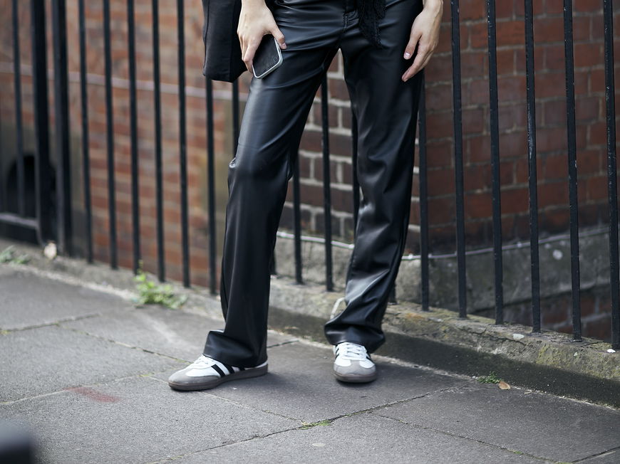 Frau trägt auf London Fashion Week weiße Retro-Sneaker und Lederhose