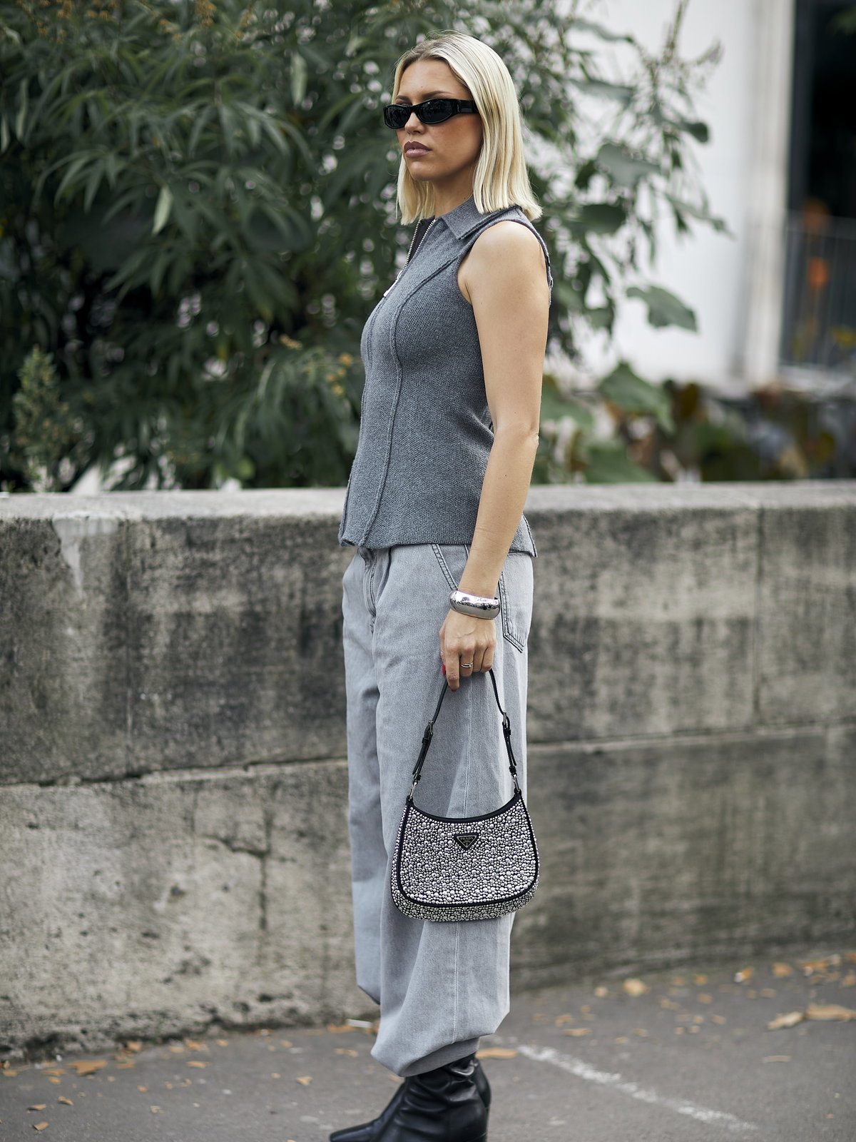 Frau trägt auf Paris Fashion Week Ankle Boots mit grauer Jeans, grauem Top und Sonnenbrille