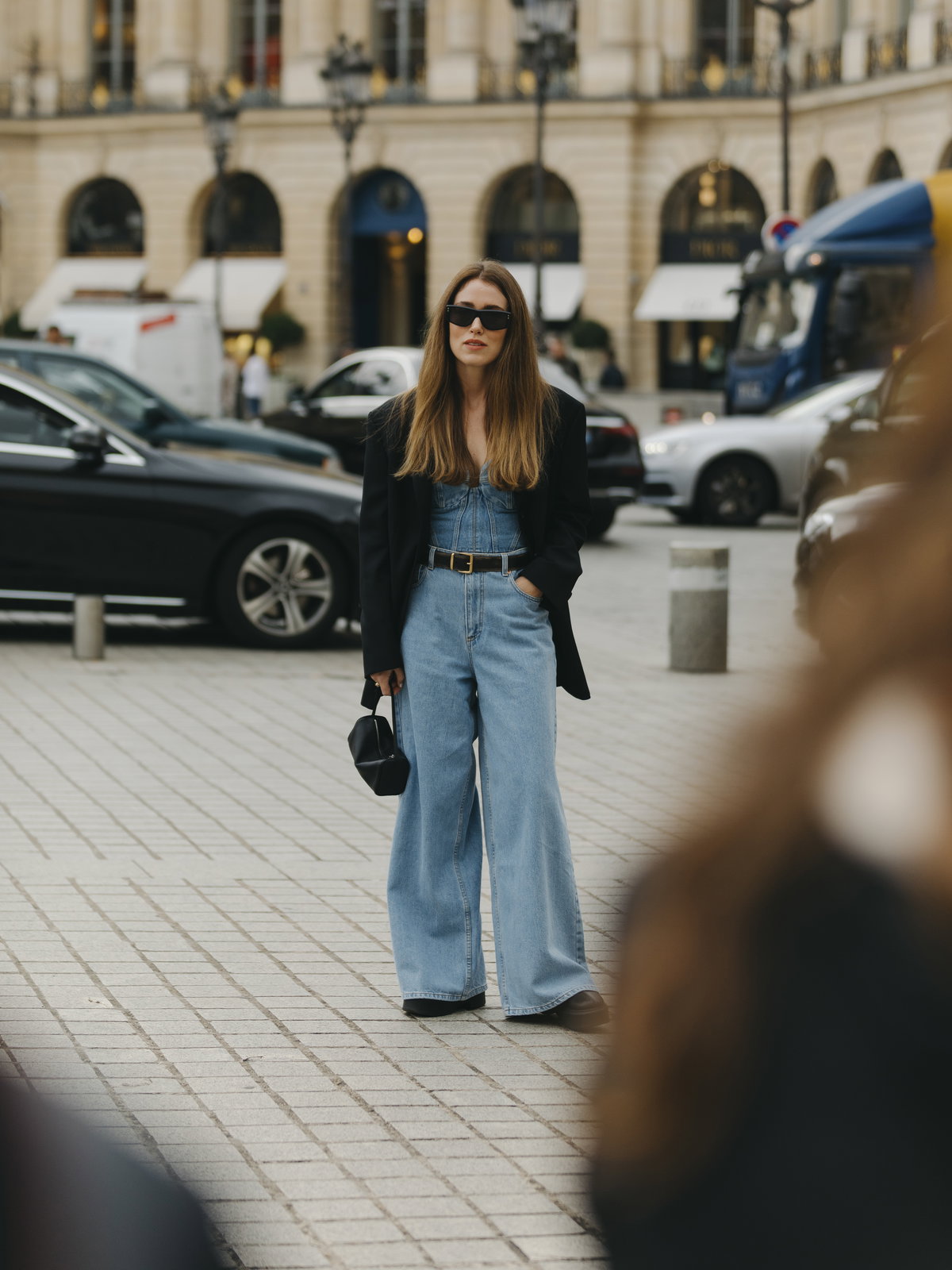 Frau trägt weite blaue Jeans mit schwarzem Blazer und Sonnenbrille sowie Jeans Top