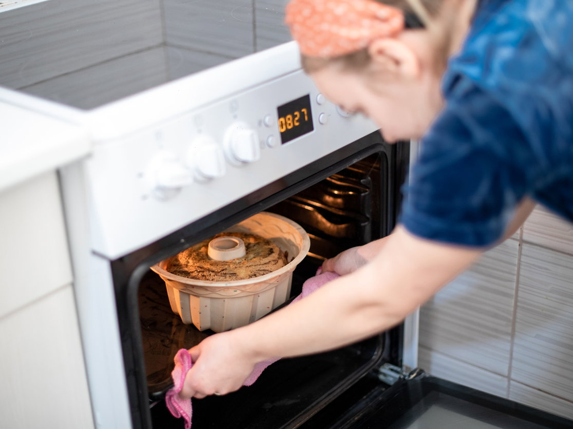 Frau tut Gugelhupf in Backofen