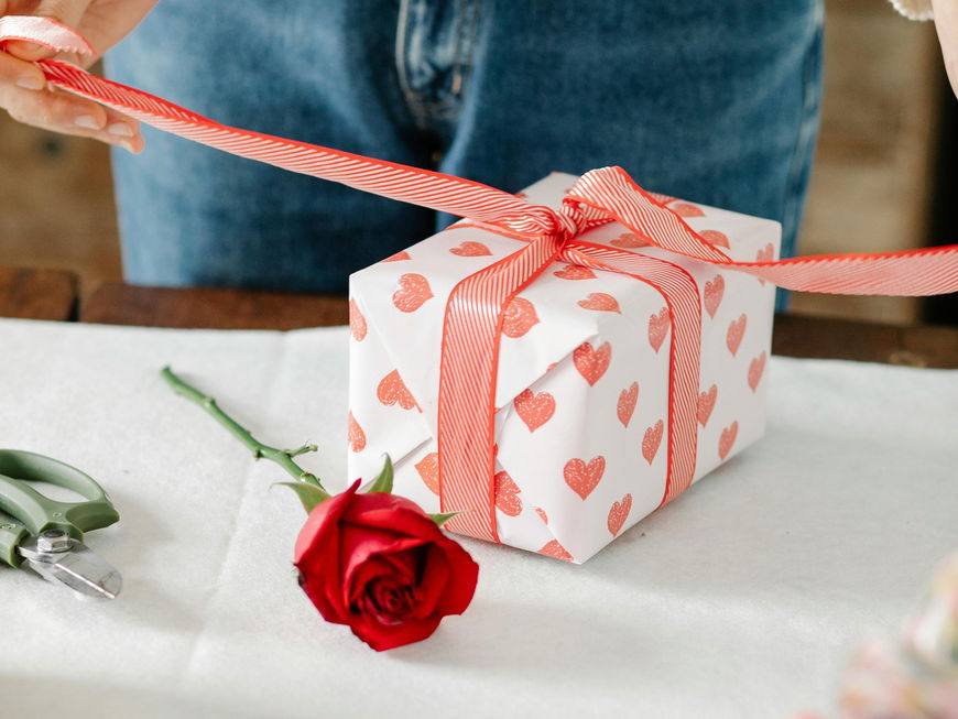 Frau packt ein Geschenk mit Herzen ein