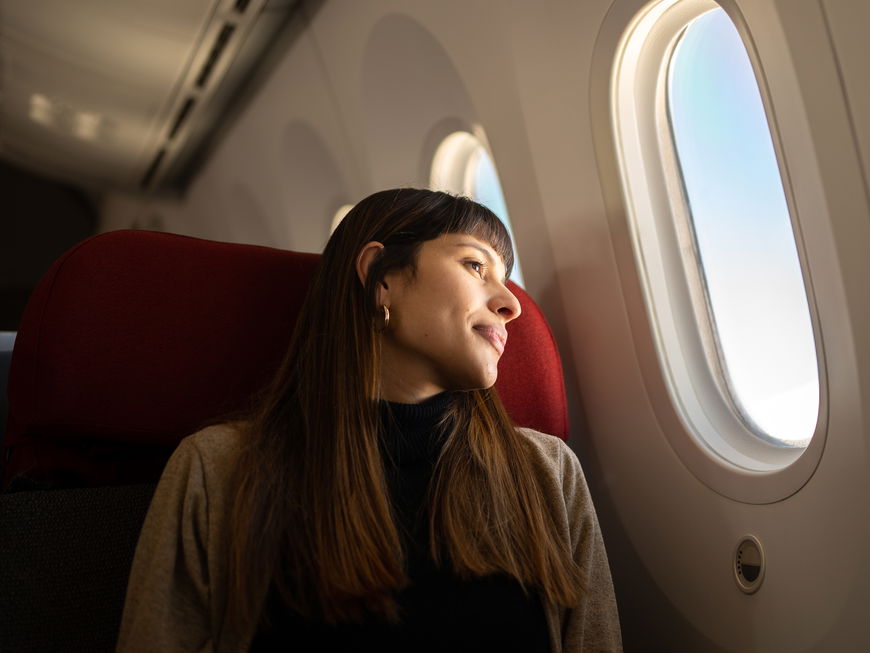 Frau sitzt im Flugzeug und guckt aus dem Fenster