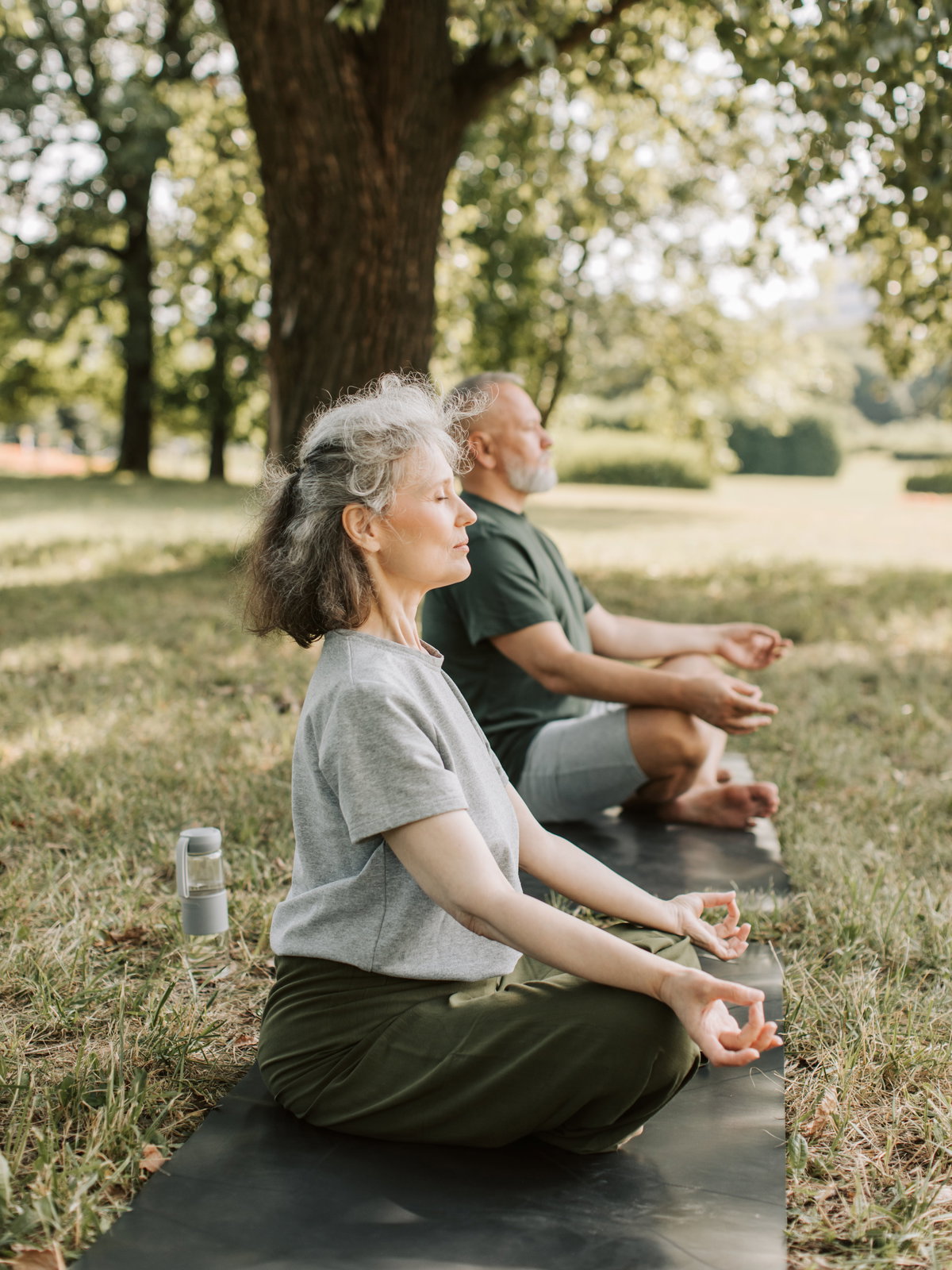 Älteres Paar macht Yoga auf einer Wiese.