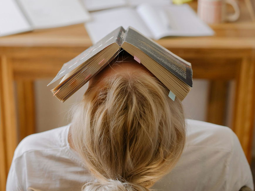 Gestresste Frau mit Buch auf dem Kopf