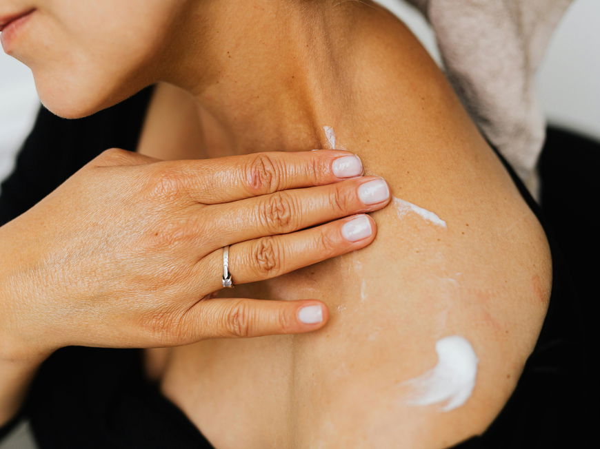 Frau cremt sich mit Bodylotion ein