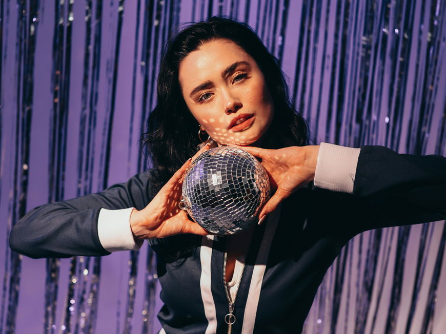 Was anziehen zur 80er Mottoparty: Frau mit Discokugel