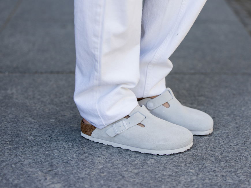 Birkenstock Boston in Grau mit einer weißen Hose kombiniert.