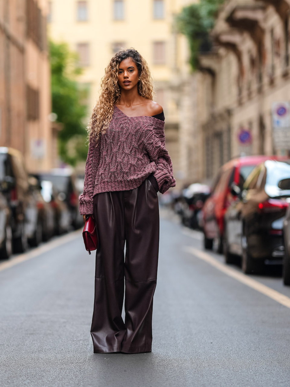Eine Frau trägt einen dunkelroten Strickpullover mit einer Lederhose.
