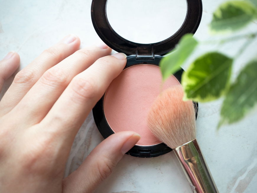 Blush in Puderform mit einem Pinsel.