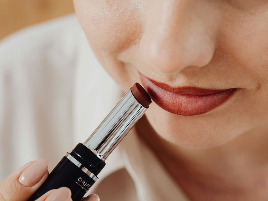 Frau schminkt sich mit Lippenstift.