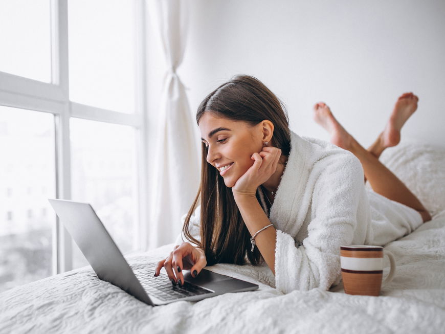 Frau auf dem Bett am Laptop
