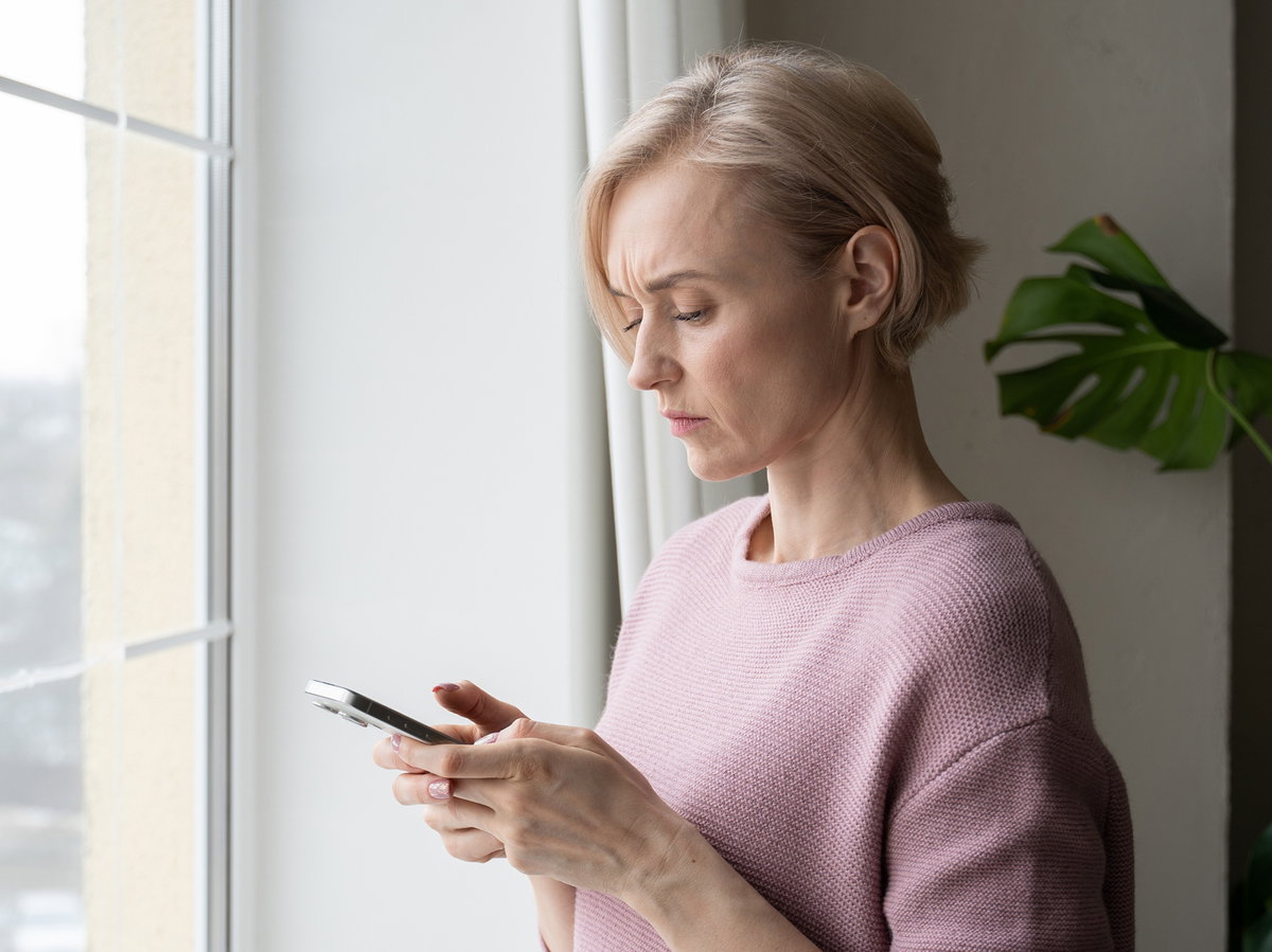 Frau guckt skeptisch auf ihr Handy.
