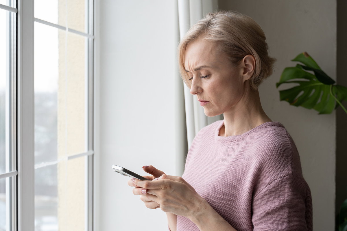 Frau guckt skeptisch auf ihr Handy.