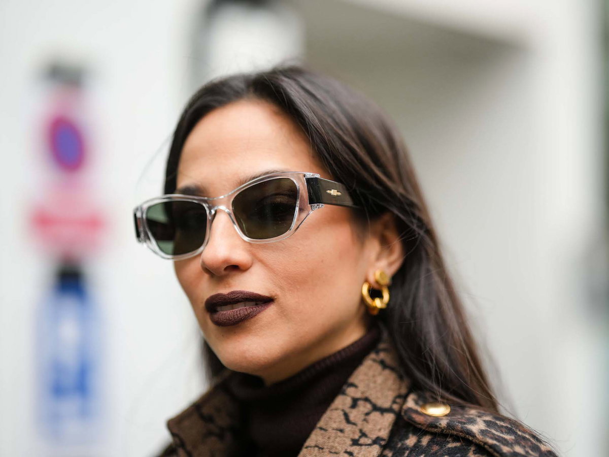 Frau trägt kastanienbraunen Lippenstift und eine Sonnenbrille.