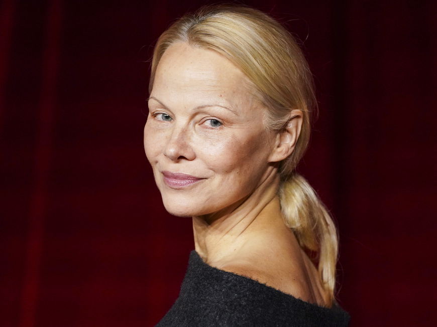 Pamela Anderson guckt über die Schulter nach hinten.