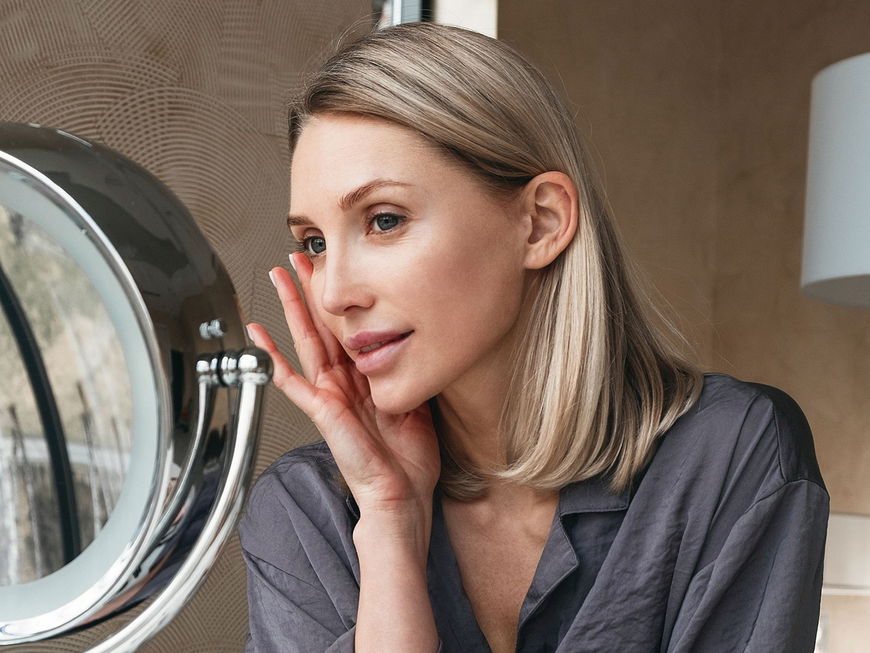 Frau trägt Make-up auf ihr Gesicht auf.