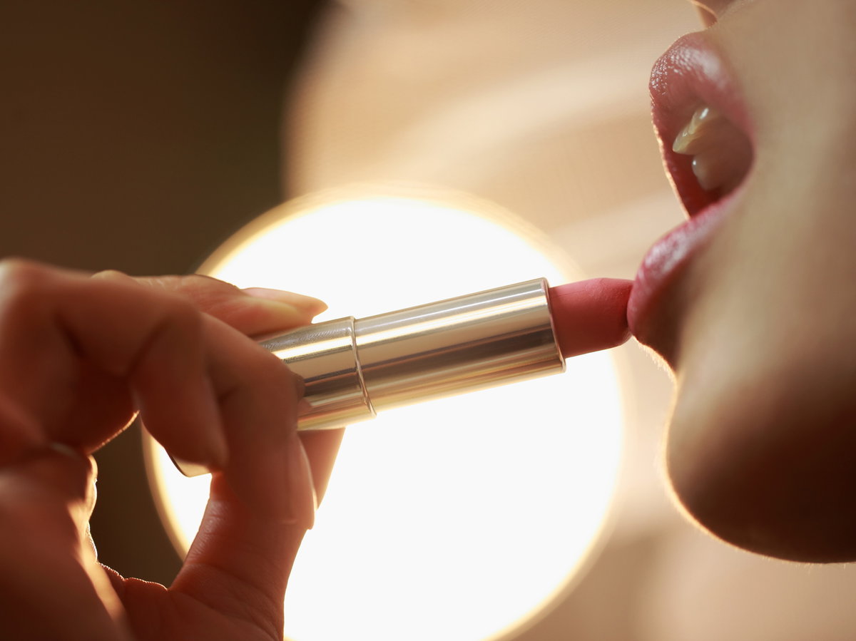 Frau trägt Lippenstift auf die Lippen auf.