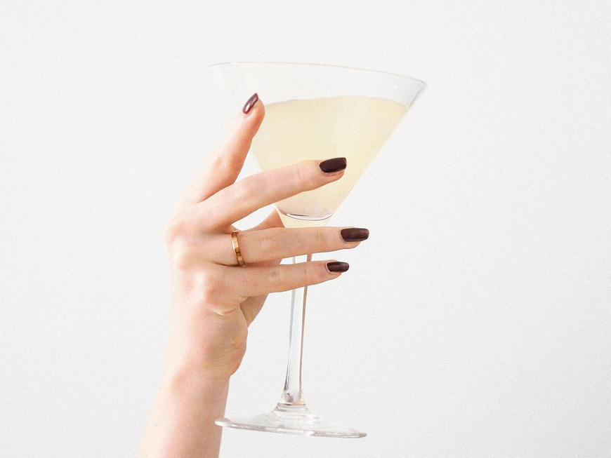 Frauenhand mit Nagellack hält Sektglas