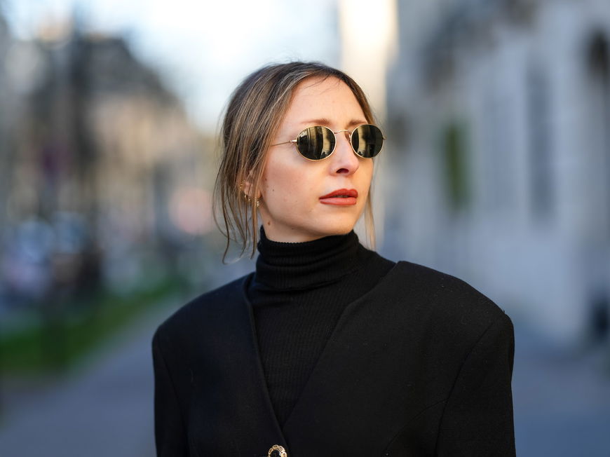 Frau mit Sonnenbrille und einem schwarzen Rollkragenshirt.