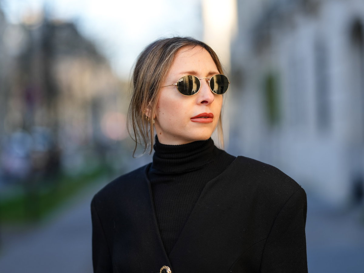 Frau mit Sonnenbrille und einem schwarzen Rollkragenshirt.