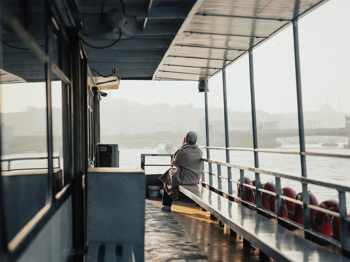 Frau sitzt auf einem Schiff und guckt aufs Wasser.
